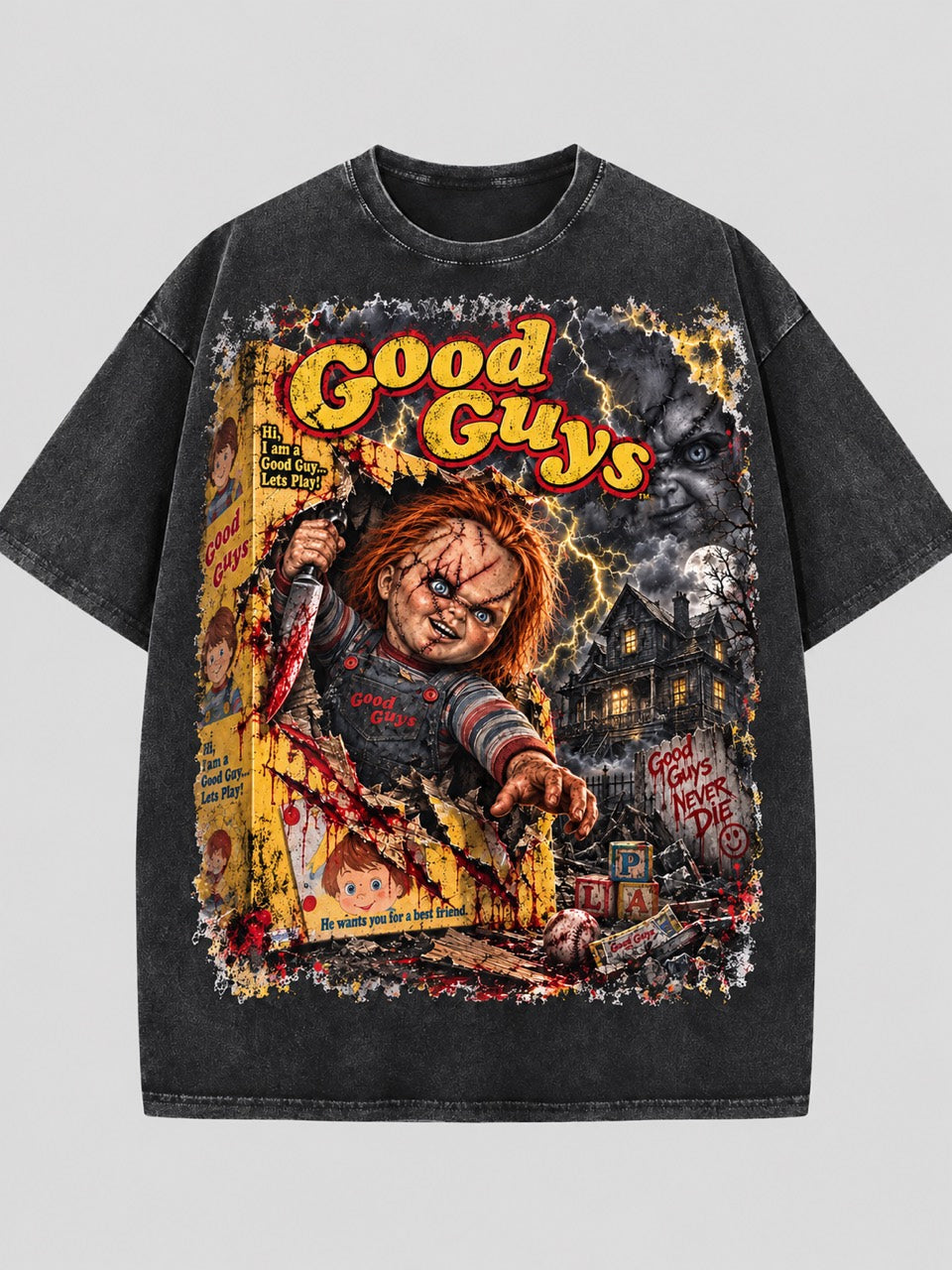 Washed dark T-shirt featuring Chucky emerging from a toy box beneath yellow and red “Good Guys” lettering, with lightning and a dark house.