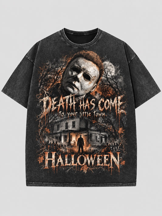 Washed dark T-shirt with a Michael Myers portrait, moonlit house, orange accents, and “Death Has Come to Your Little Town” lettering.